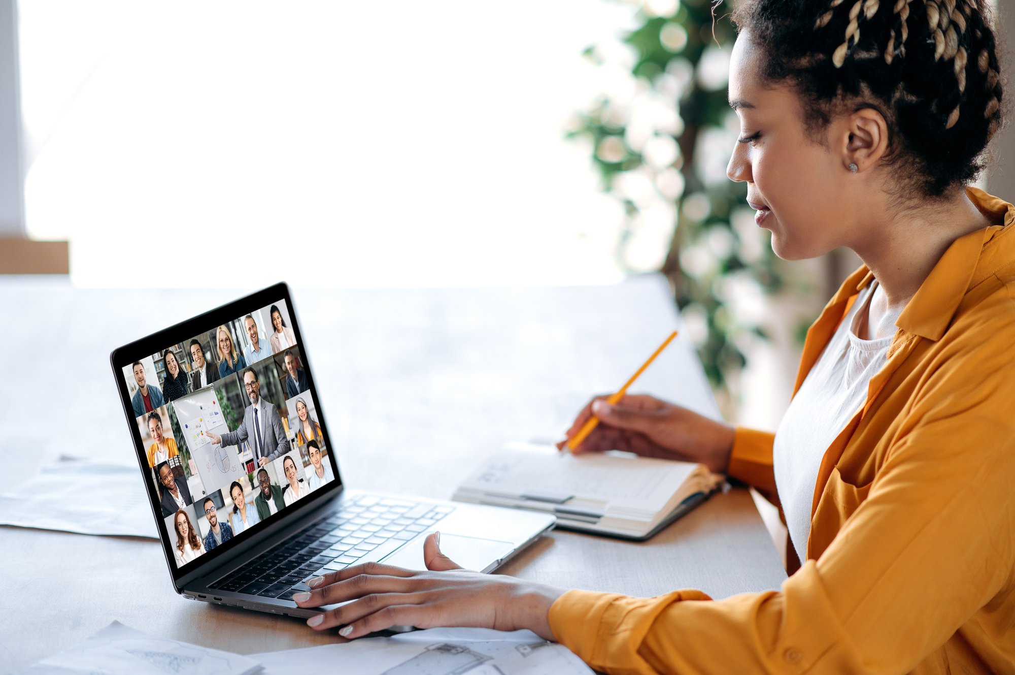Black female manager communicates with business team during video call, taking notes