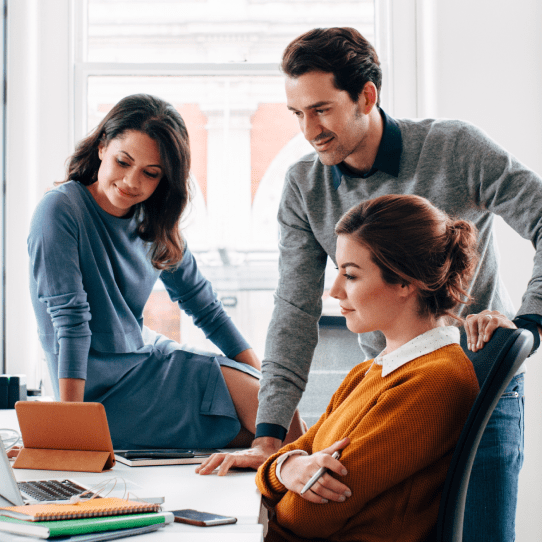 Image of three people in an office looking at a tablet