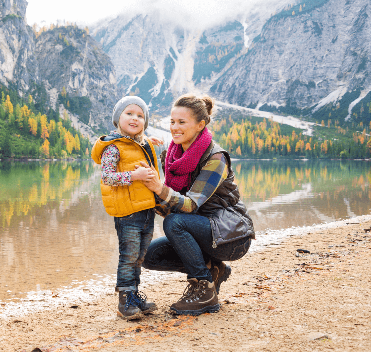 Caucasian mother with her young daughter in front of a lake and mountains.