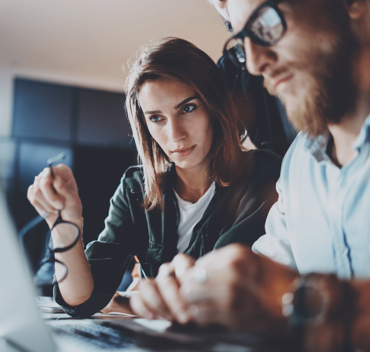 One Caucasian woman and one Caucasian man sitting at a desk together looking at a computer screen.