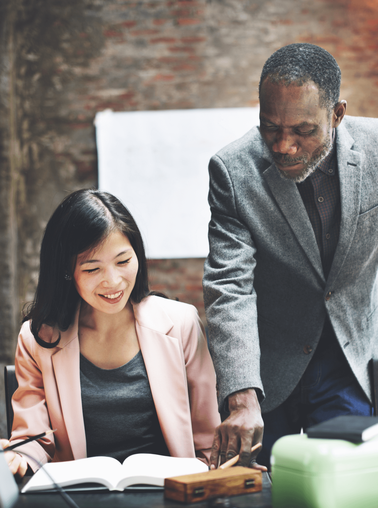 One African American man and one Asian woman working together at a desk.