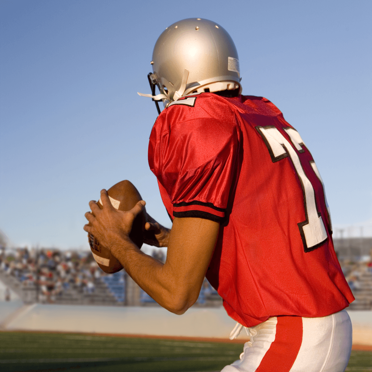 American football quarterback wearing a red jersey perparing to throw the ball. 