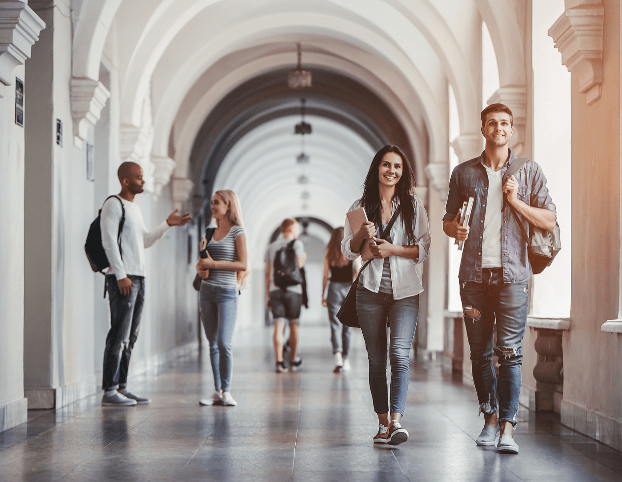 Multiracial students are walking in university hall during break and communicating.