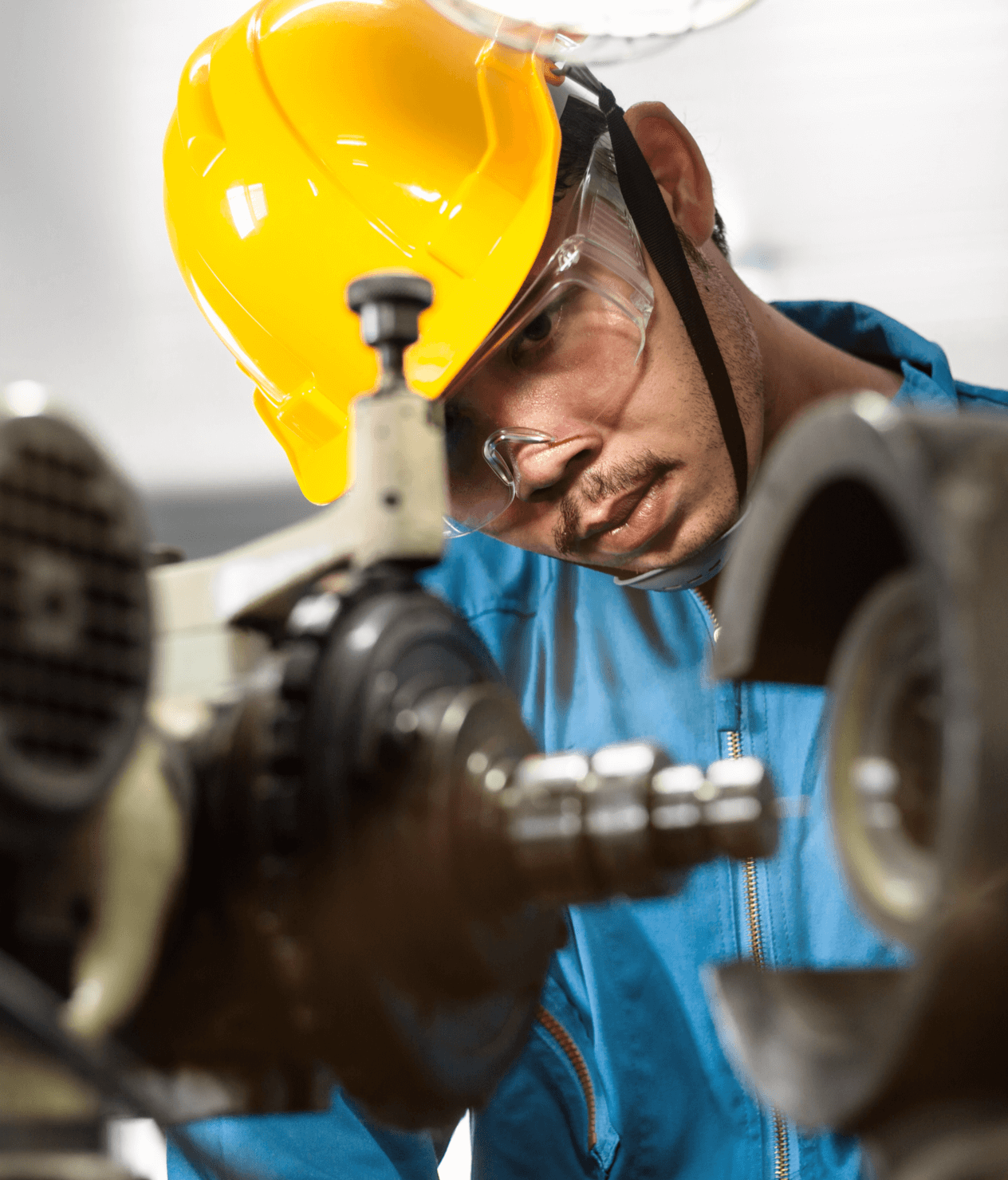 Asian factory worker staring intensely at a piece of manufacturing equipment.