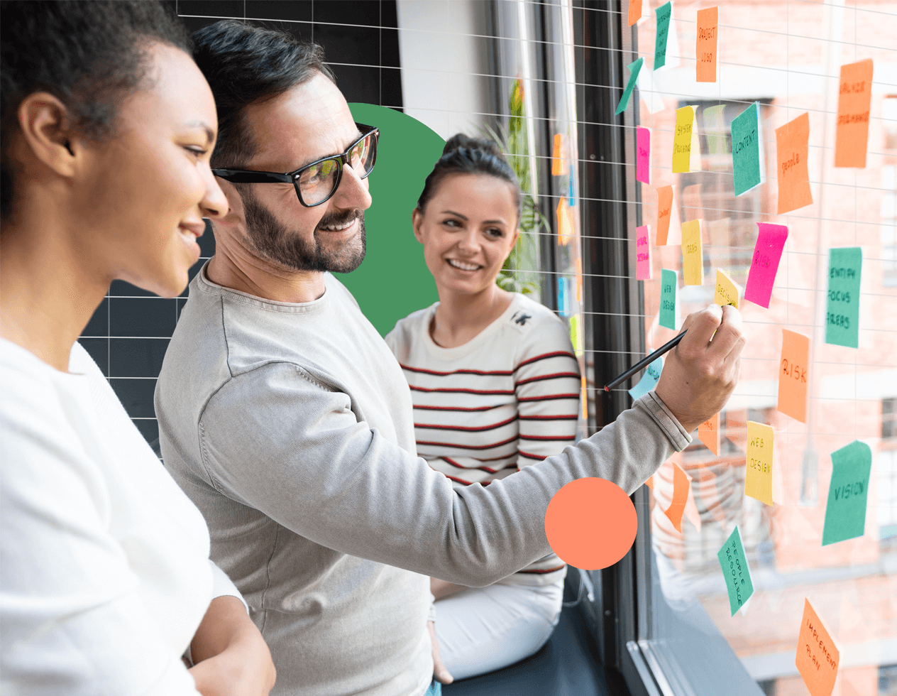 Branded image of a group of colleagues working with sticky notes on a window.