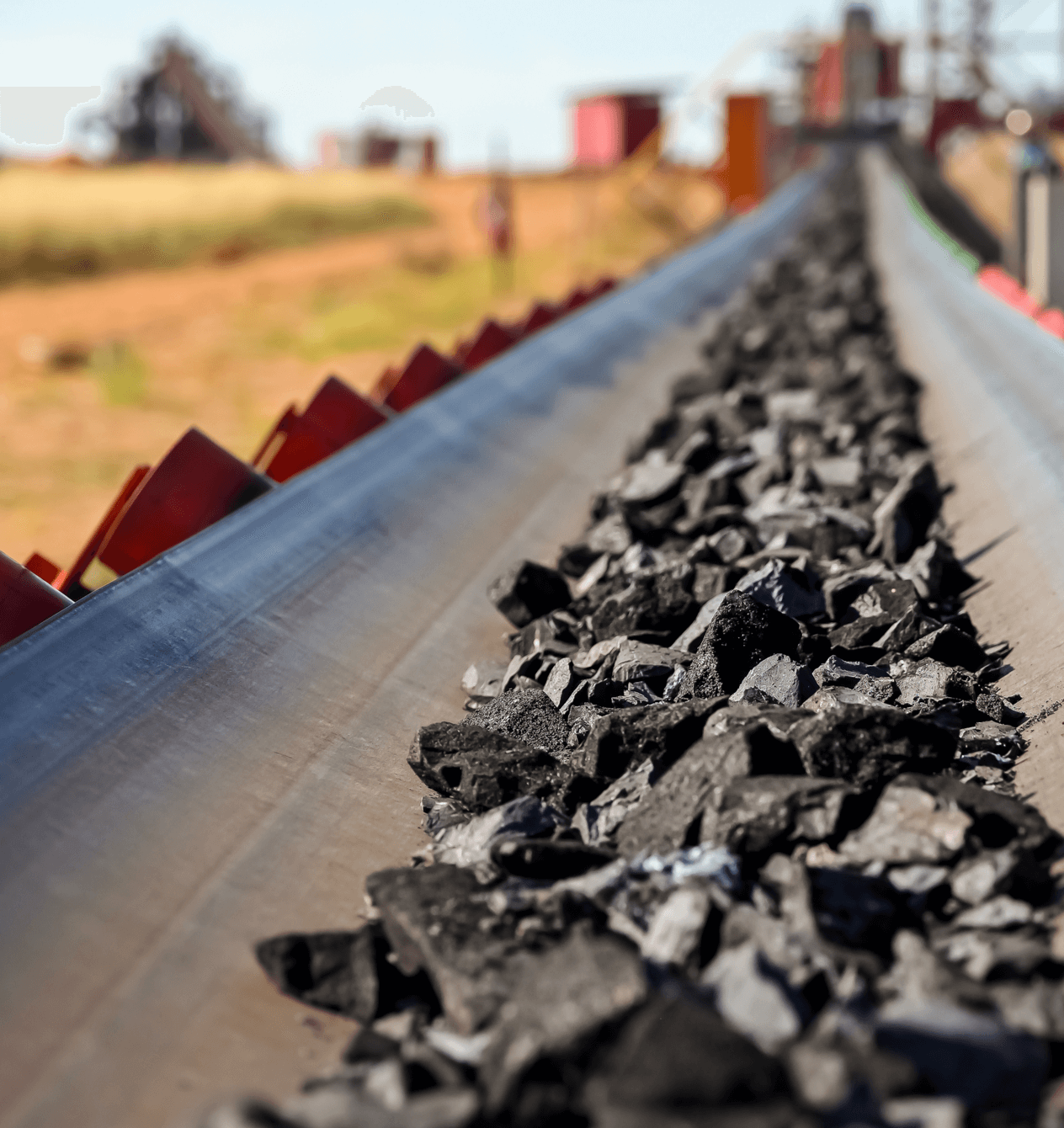 Dark rocks on a conveyor belt at a mine site.