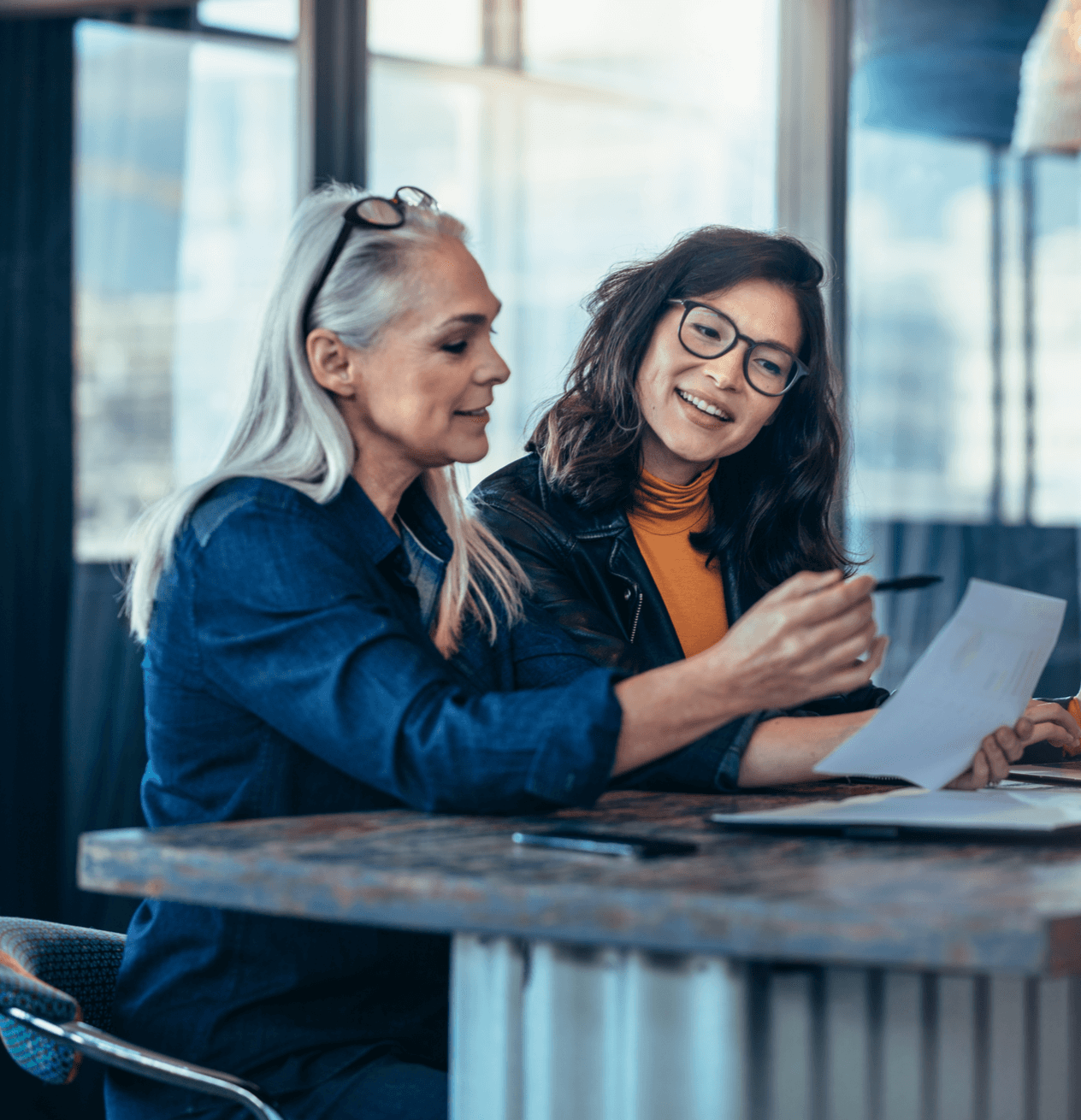 Two woman analyzing a document at a desk.