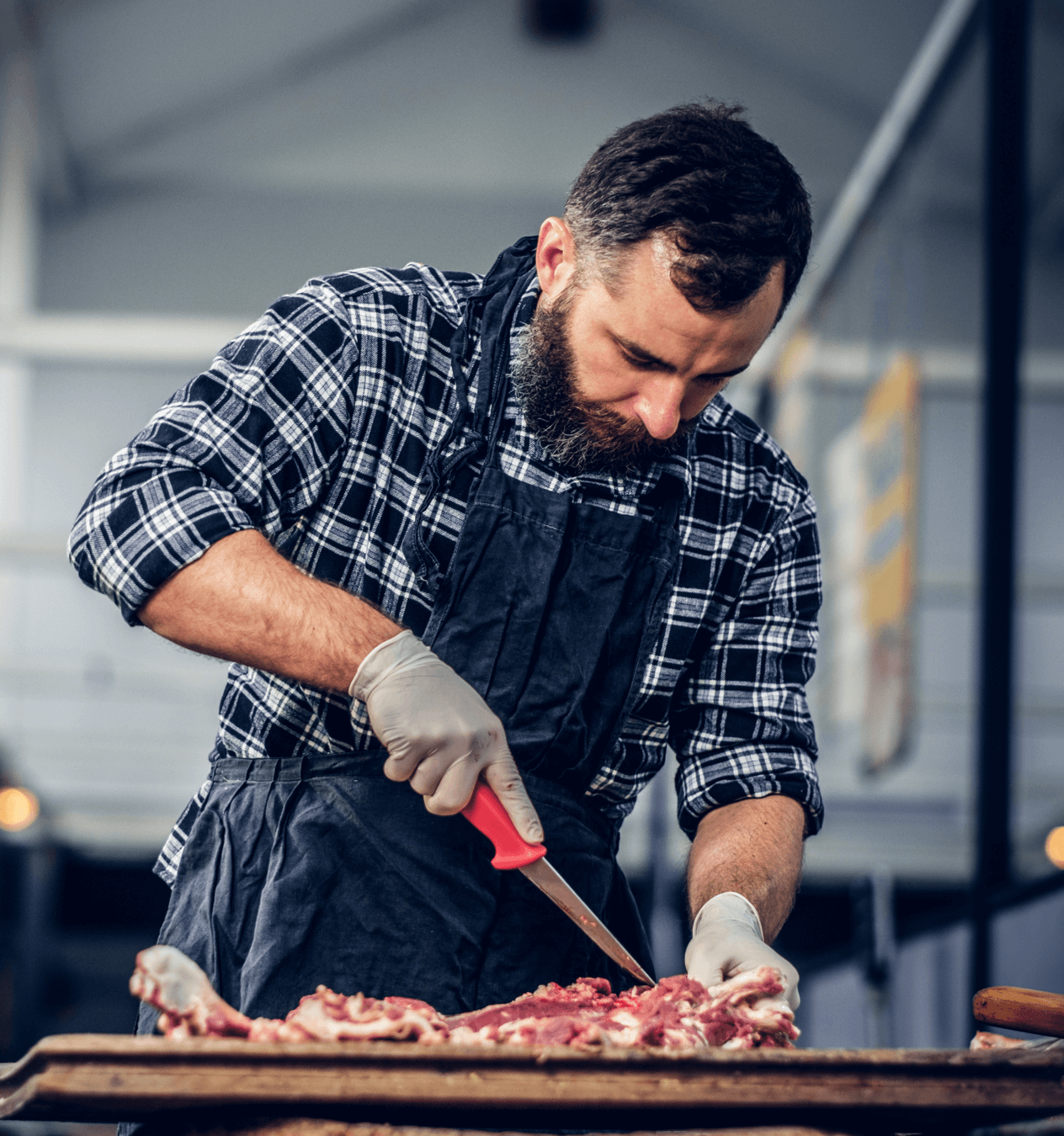 Bearded butcher preparing some raw meat for sale.