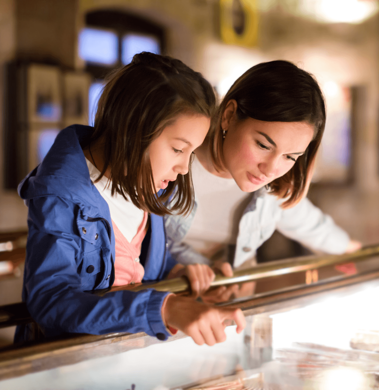 Mother and daughter examining an exhibit at a museum.
