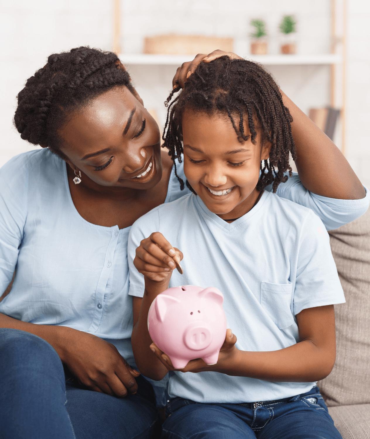 African American mother shows her young child how to use a piggy bank.