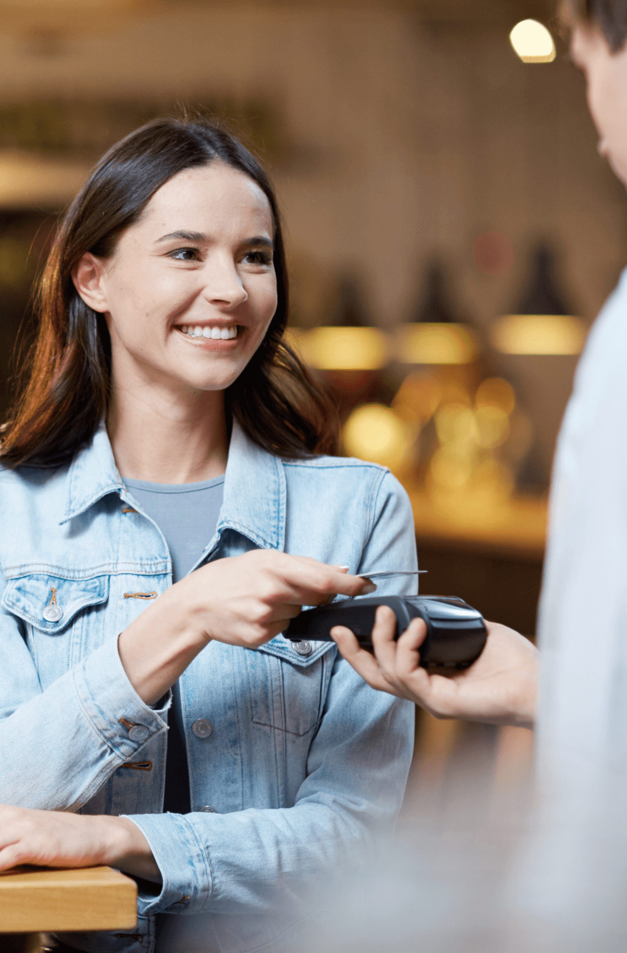 Young woman tapping her credit card while paying at a restaurant.