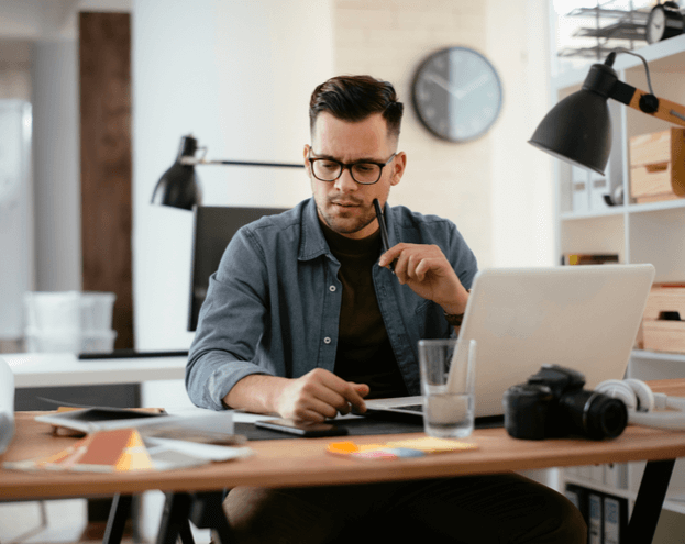 A pensive man in his office, working, in front of his laptop. 