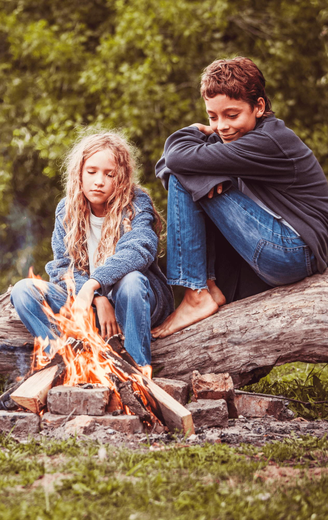 Two children sitting by a campfire.