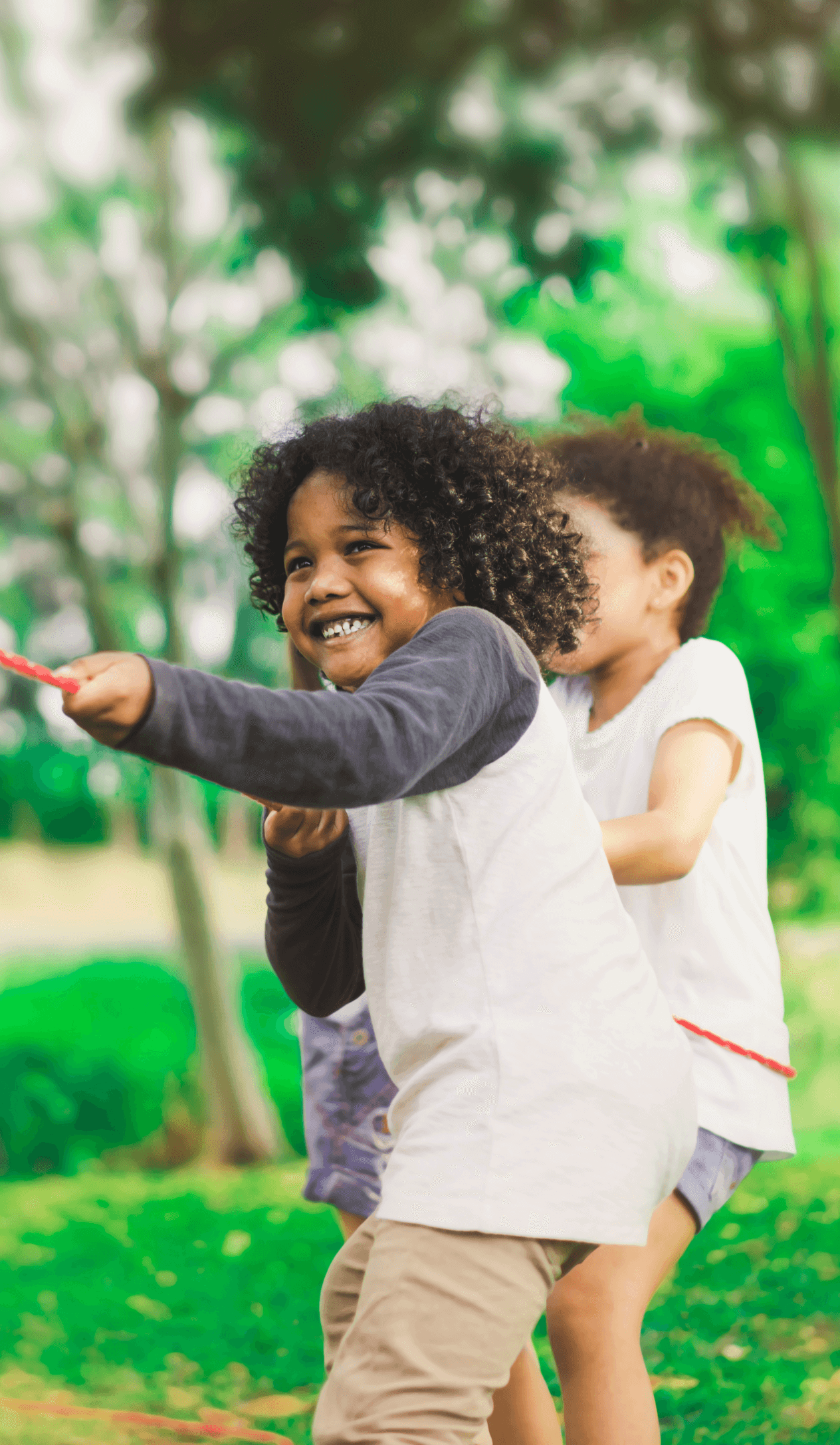 Kids playing tug of war in a park.