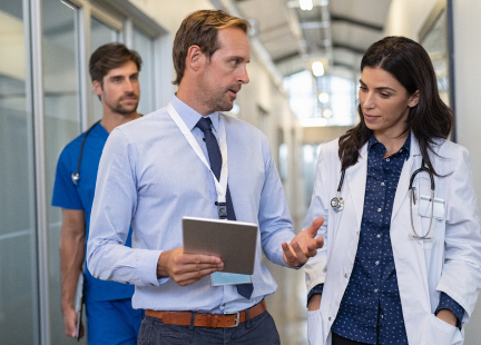 Image of a doctor, nurse and a man walking and talking down a hallway