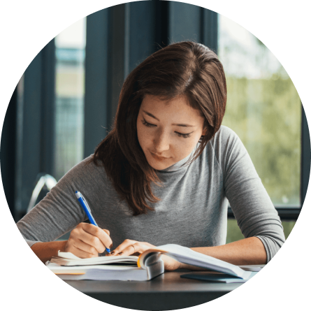 Image of a woman sitting at a desk writing in a notebook