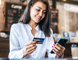 Image of a woman holding a credit card and a cellphone