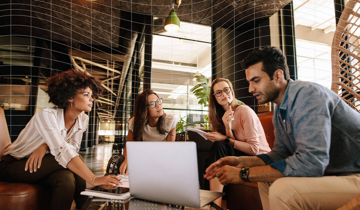 Group of four people sitting and looking at a laptop.