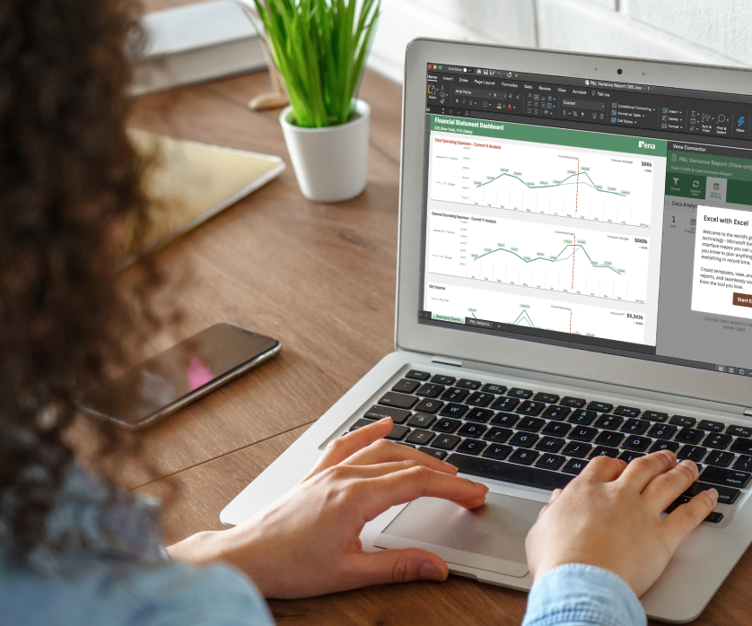 Woman typing on laptop with graphs on screen.