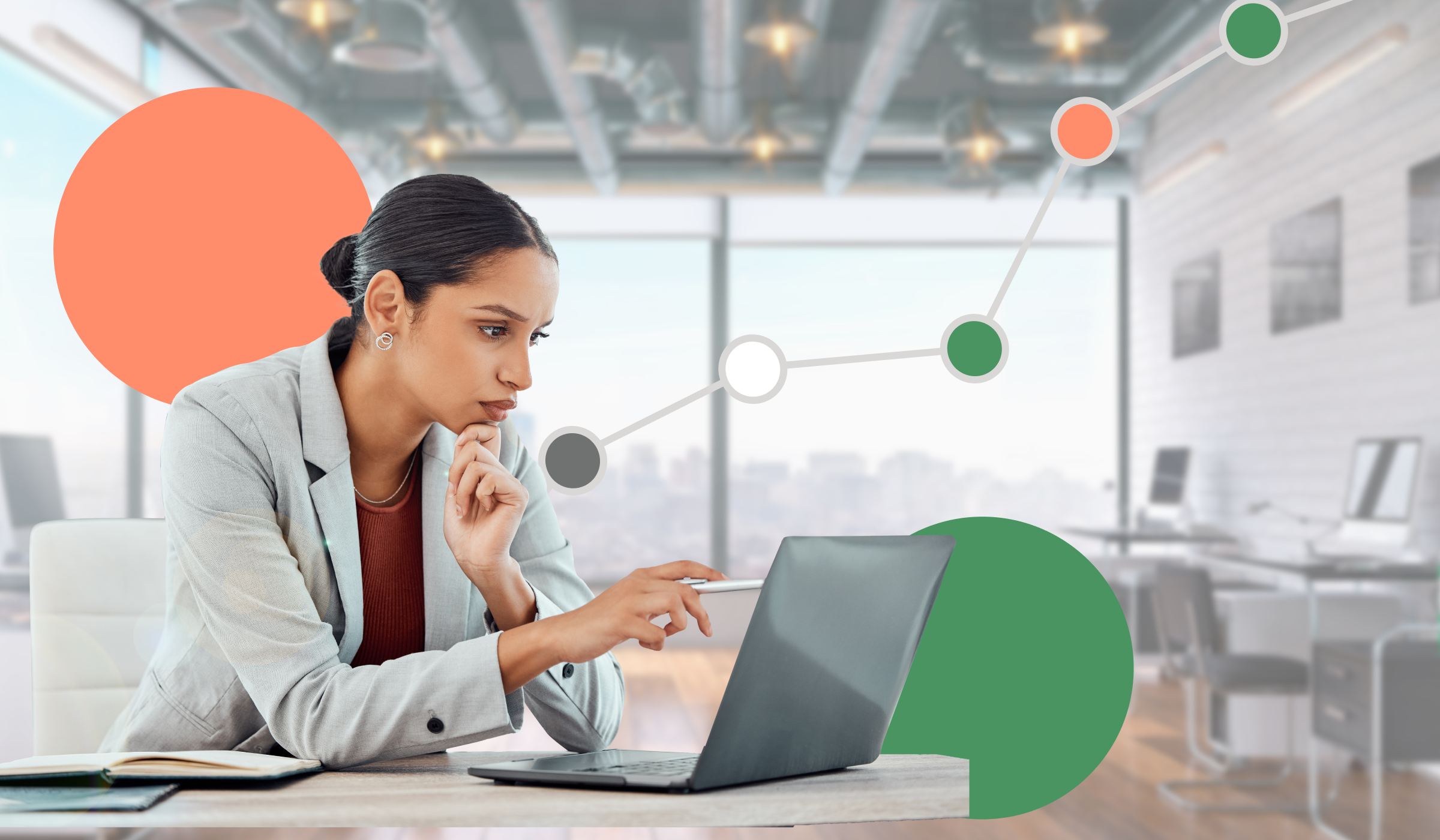 A woman sitting a desk in front of a window working on a laptop.