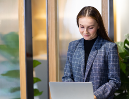 Image of a woman standing at a desk on a laptop